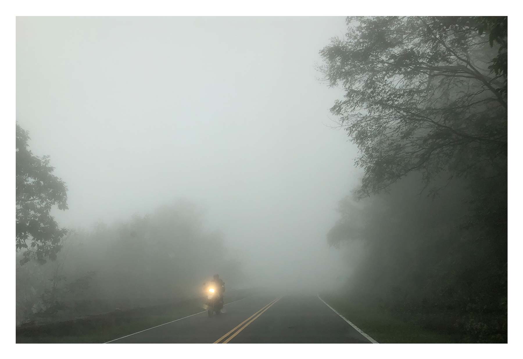 A motorcycle drives out of fog